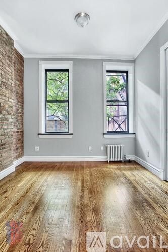 A room with wooden floors and two windows.