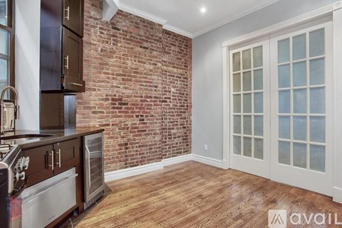 A kitchen with a brick wall and wooden floors.