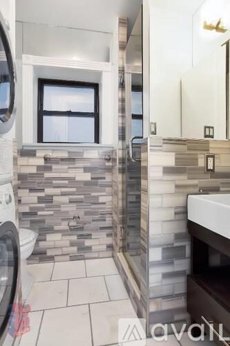 A bathroom with a tiled wall and a window.