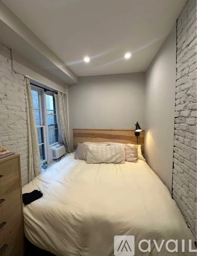 A bedroom with a bed, nightstand, and window.