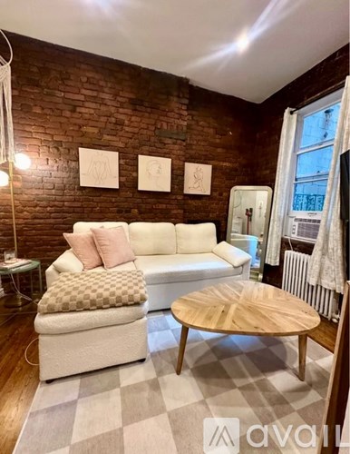 A living room with a white couch, a wooden coffee table, and a brick wall.
