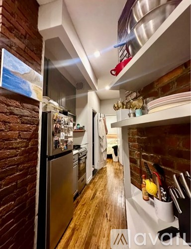 A kitchen with a brick wall and wooden floors.
