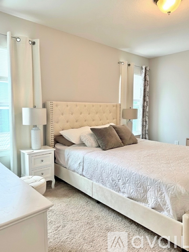 A white bedroom with a large bed and a nightstand.