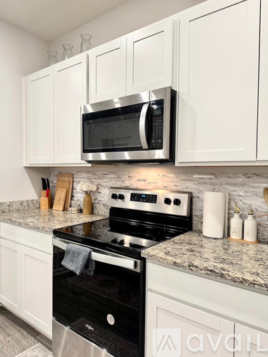 A kitchen with a black stove and white cabinets.