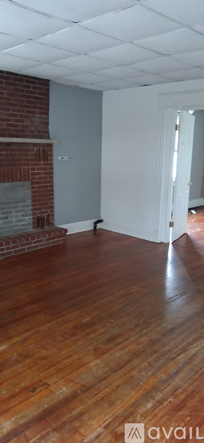 A room with a brick fireplace and wooden floors.