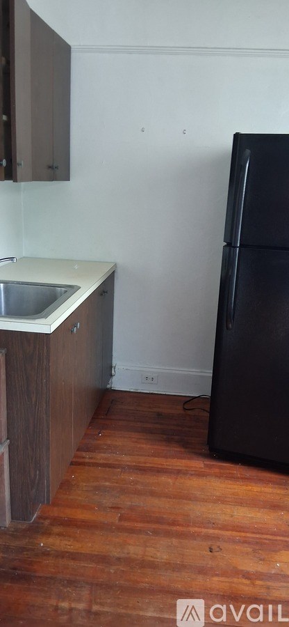 A kitchen with a black fridge and wooden floors.