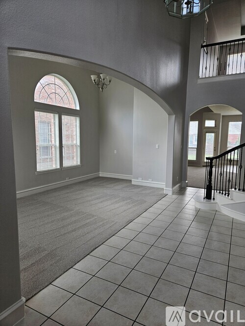 A spacious room with a tiled floor and a large arched window.