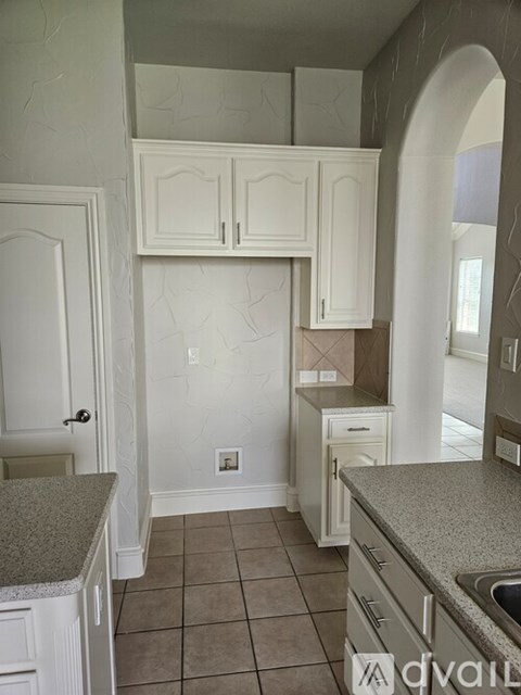 A kitchen with white cabinets and a granite counter.
