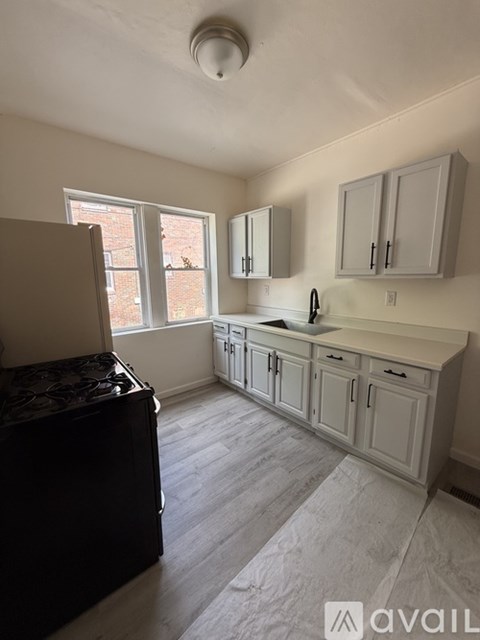 A kitchen with a black refrigerator and white cabinets.