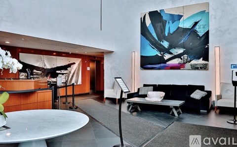 A modern living room with a large abstract painting on the wall.