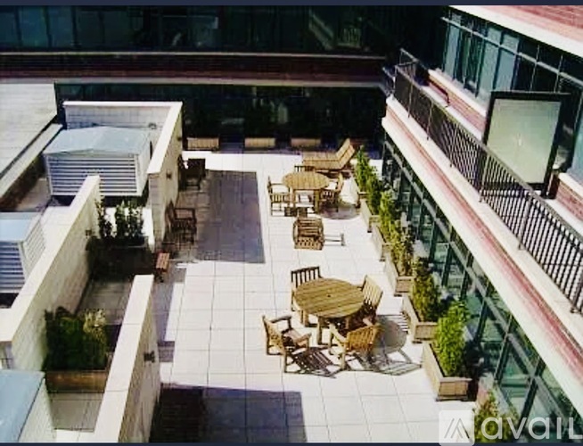 A patio with tables and chairs is surrounded by buildings.
