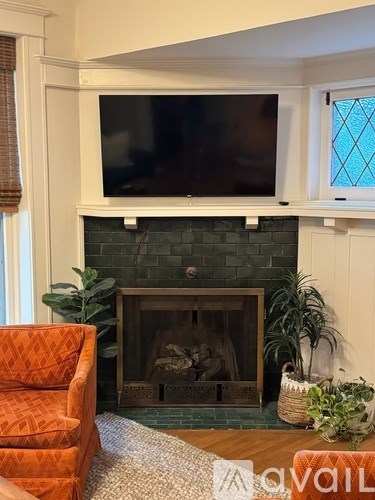 A living room with a fireplace and a television mounted above it.