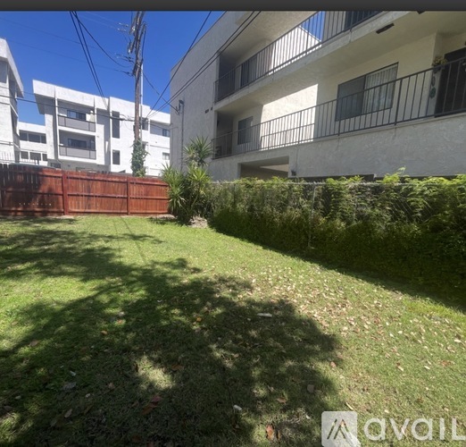 A grassy area in front of a building with a fence and bushes.
