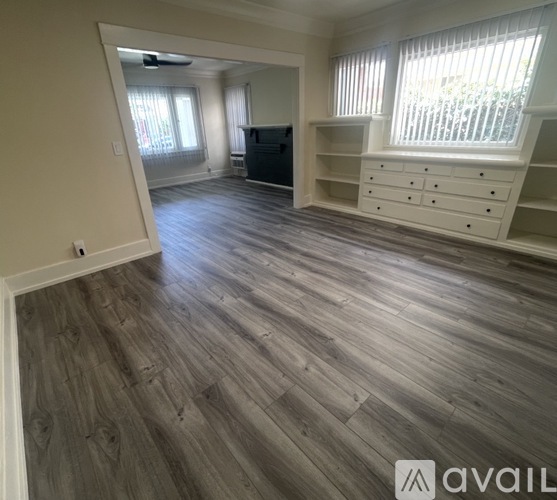 A spacious room with wooden flooring and built-in shelves.