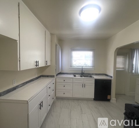 A kitchen with white cabinets and a black fridge.