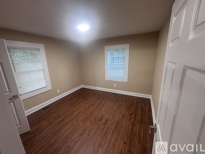 A room with wooden flooring and a window with blinds.