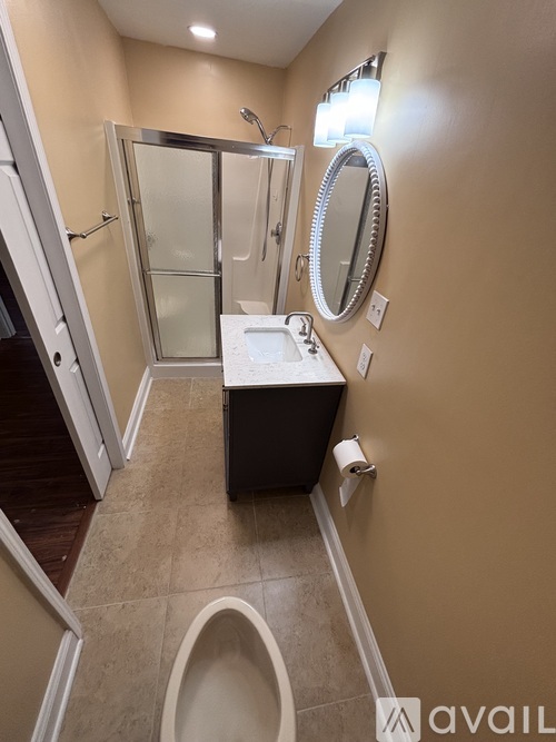 A bathroom with a toilet, sink, mirror, and shower.