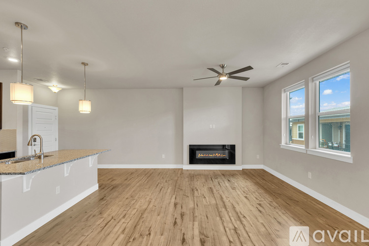 A spacious living room with a fireplace and a ceiling fan.