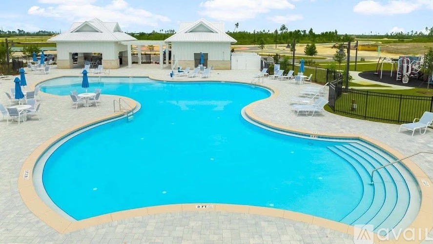 A large outdoor swimming pool with lounge chairs and a building in the background.