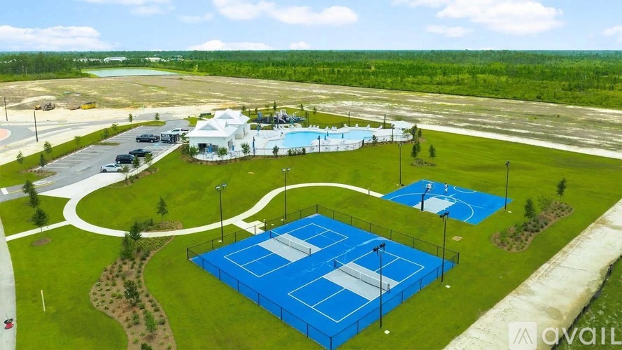 A tennis court is surrounded by a green lawn and a white building.
