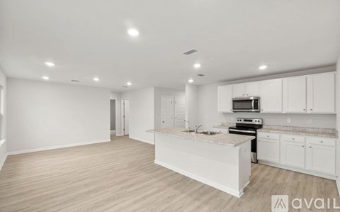 A spacious kitchen with white cabinets and a wooden floor.
