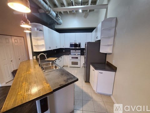 A kitchen with a wooden counter top and white cabinets.
