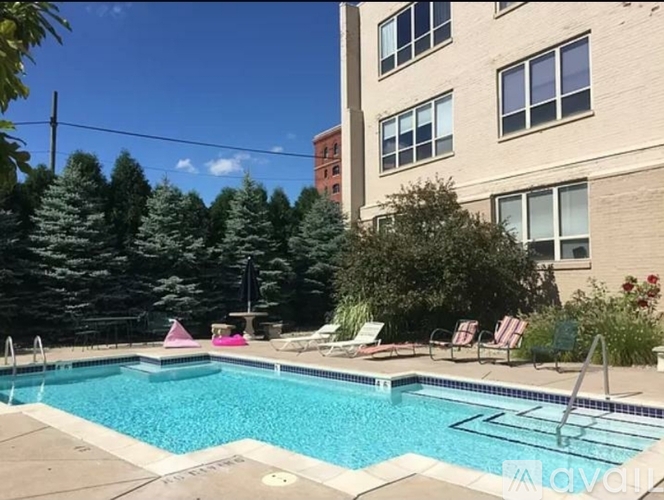 A pool surrounded by trees and chairs.