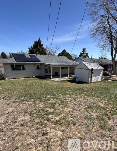 A house with solar panels on the roof is surrounded by a grassy area.