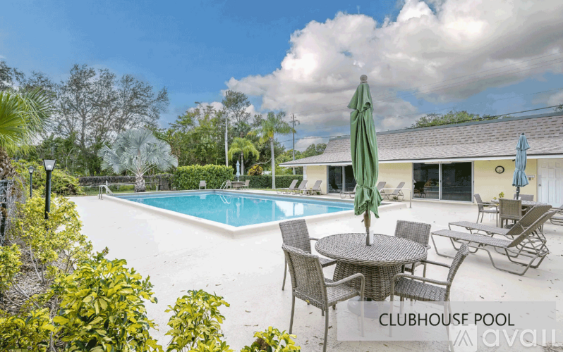 A pool area with a table and chairs and a building in the background.