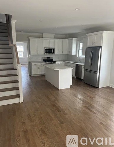 A kitchen with white cabinets and a wooden floor.