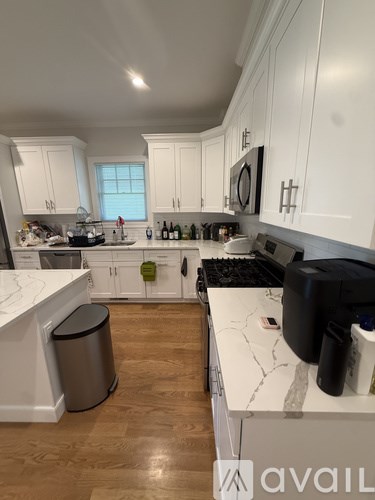 A kitchen with white cabinets and a marble countertop.
