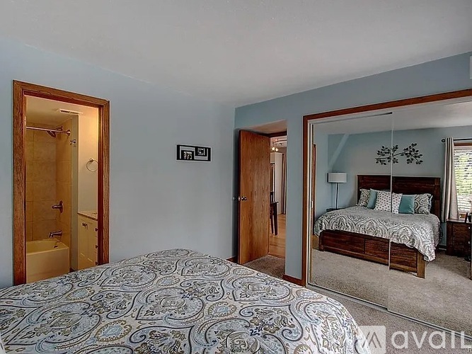 A bedroom with a patterned bedspread and a bed with a wooden headboard.