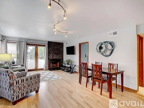 A living room with a fireplace, a couch, a chair, a table and a mirror.