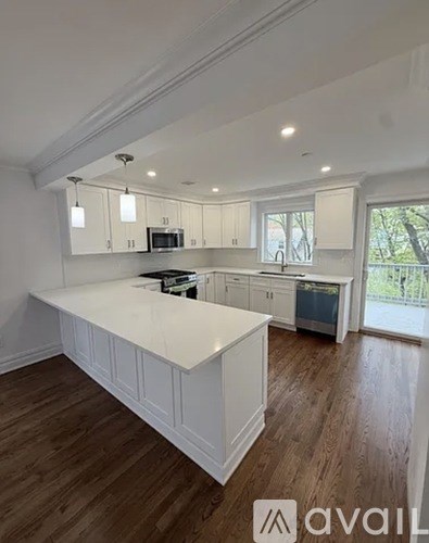 A kitchen with white cabinets and a wooden floor.