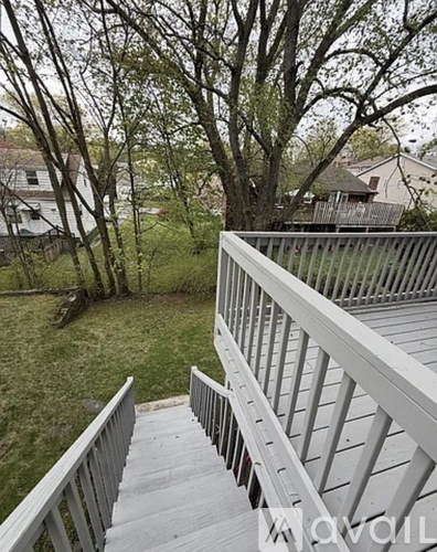A deck with a railing and steps leading to a grassy area with trees.