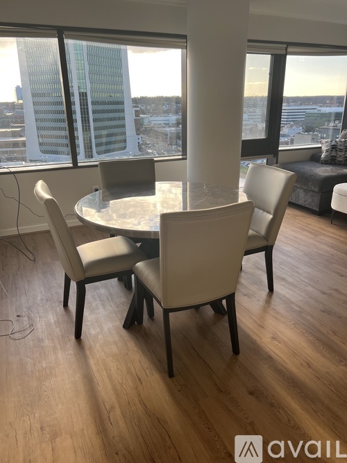 A round table with four chairs in front of a large window.
