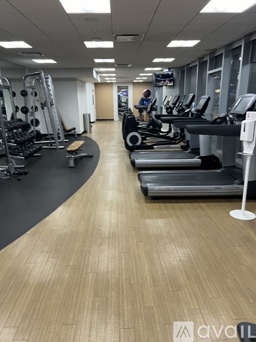 A gym with treadmills, weights, and a person working out.