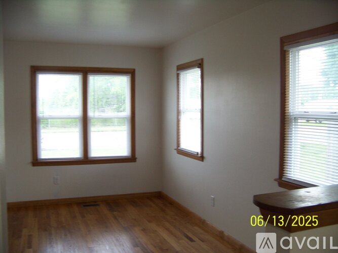 A room with wooden floors and two windows with blinds.