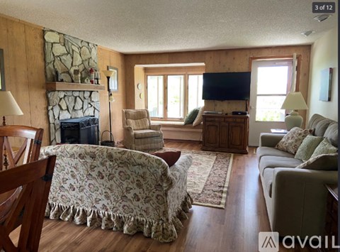 A living room with a stone fireplace and a flat screen TV.