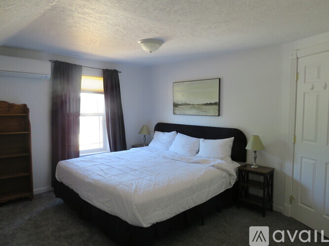 A bedroom with a large bed and a painting on the wall.