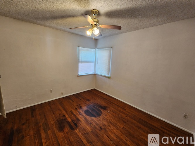 A room with a ceiling fan and wooden flooring.