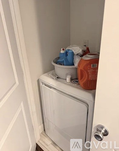 A white washing machine is in a small space next to a door.