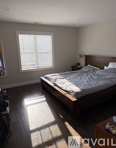 A bedroom with a large bed and a window letting in sunlight.