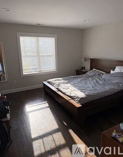 A bedroom with a large bed and a window letting in sunlight.