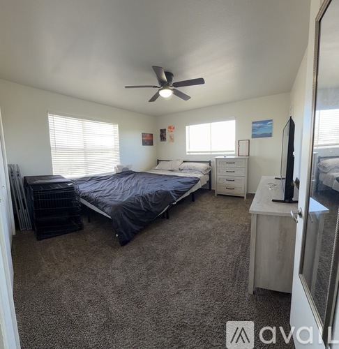 A bedroom with a bed, dresser, and ceiling fan.