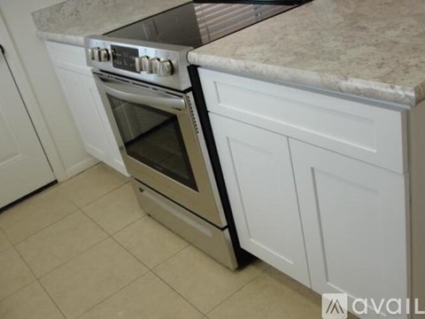 A kitchen with a stainless steel oven and white cabinets.