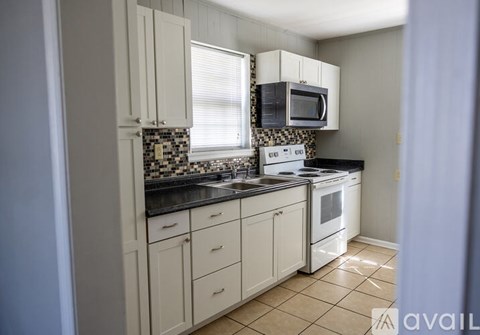 A kitchen with white cabinets and black countertops.