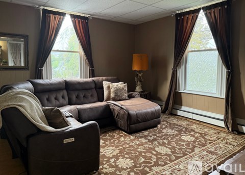 A living room with a grey sofa and a patterned carpet.