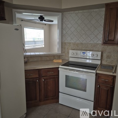 A kitchen with a white stove top oven and a white refrigerator.