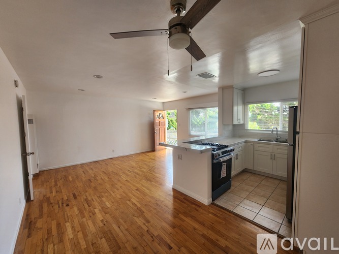 A kitchen with a fan and wooden floors.